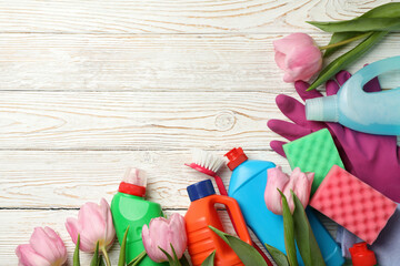 Detergents, sponges and tulips on wooden background