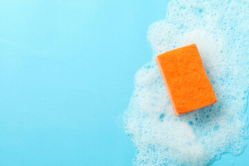 Orange sponge and foam on blue background - obrazy, fototapety, plakaty