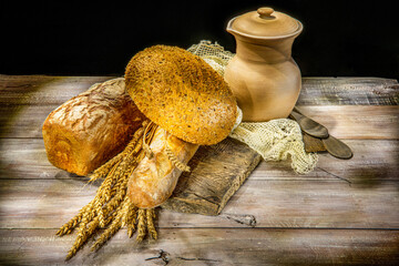 Bread, bun, wheat, clay jug on wooden background
