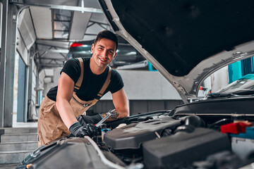 Fototapeta na wymiar Mechanic working on engine in auto repair shop.
