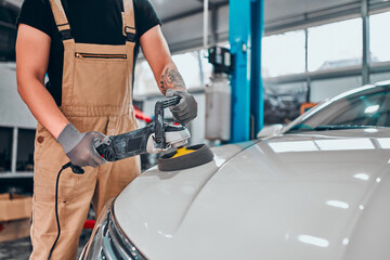Car detailing. Hands with orbital polisher in auto repair shop.