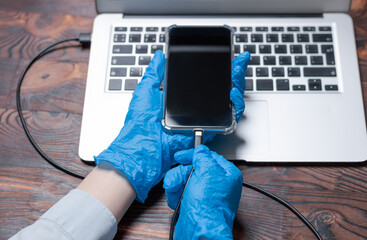 Image of a smartphone that is connected to a laptop for diagnostics. Repair of equipment. Top view.