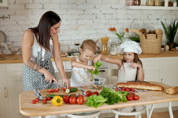 Mom cooks lunch with the kids. A woman teaches her daughter to cook from her son. Vegetarianism and healthy natural food