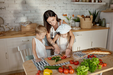 Children learn how to prepare a salad in the kitchen. Family day off, lunch with your own hands. Mom and young cooks