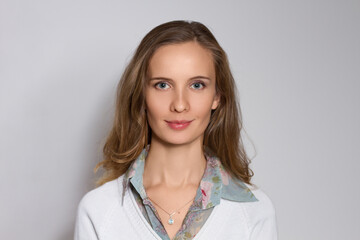 Portrait of the beautiful smiling woman with long hair on gray background.