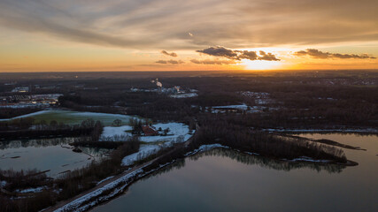 Aerial view of a beautiful and dramatic sunset over a forest lake reflected in the water, landscape drone shot. Blakheide, Beerse, Belgium. High quality photo