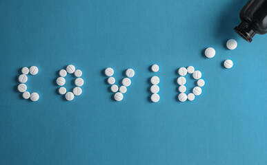 Fototapeta na wymiar Inscription Covid 19 from letters made of pills on blue background.