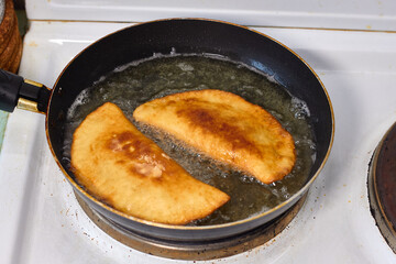Process with  fried in sunflower oilof homemade qutab or chebureki, calzone with minced meat and onion. Process of making food at the kitchen. Azerbaijani, Tatar, Caucasian, Greek cuisine. 