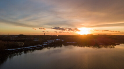 Aerial view of a beautiful and dramatic sunset over a forest lake reflected in the water, landscape drone shot. Blakheide, Beerse, Belgium. High quality photo