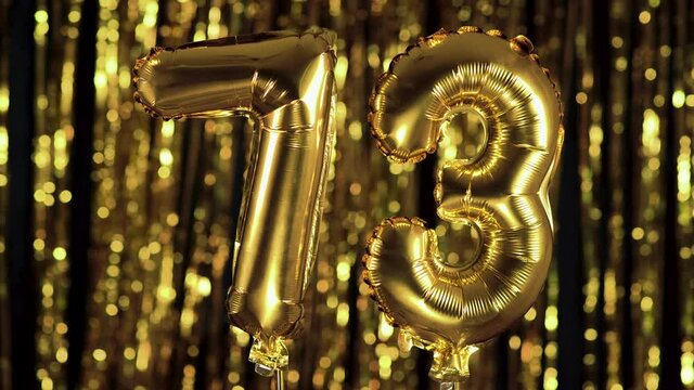 The golden number 73 seventy three is made from an inflatable ball on a yellow background. One of the complete set of numbers. Birthday, anniversary, date concept
