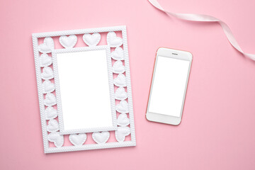 Valentine's Day composition. Photo frame with hearts and mobile phone on pastel pink background. Wedding. Birthday. Happy woman's day. Mothers Day. Flat lay, copy space