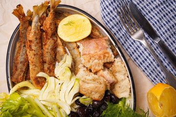 Smelt fried with few slices of lemon, olives, 
fennel and bread. White background. Close-up. View from above.