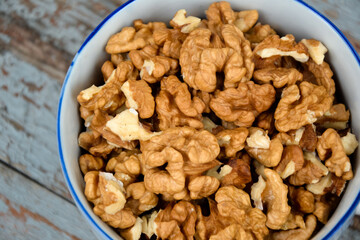 Walnuts. Walnut kernels. Clean organic walnuts. Nuts in the cup on vintage blue wooden background. Walnut tree fresh fall harvest.