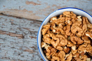 Walnuts. Walnut kernels. Clean organic walnuts. Nuts in the cup on vintage blue wooden background. Walnut tree fresh fall harvest.