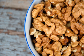 Walnuts. Walnut kernels. Clean organic walnuts. Nuts in the cup on vintage blue wooden background. Walnut tree fresh fall harvest.