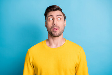 Portrait of attractive cheerful funny crazy guy grimacing looking aside isolated over bright blue...