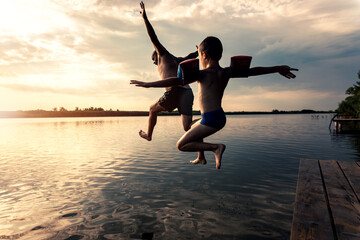 Father with his son enjoying in summer day jumping in lake.