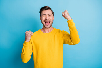 Portrait of impressed cheerful handsome guy fists up open mouth celebrate isolated on blue color background
