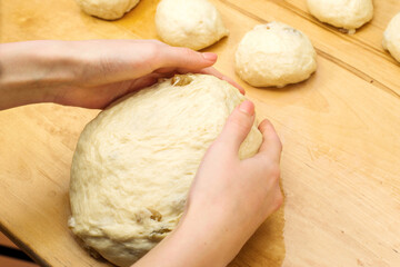 Female hands knead dough on the kitchen table. Homemade bun dough. homemade baking