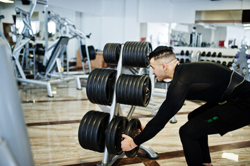 Fototapeta na wymiar Muscular arab man training with dumbbells in modern gym.