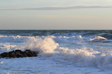 waves and sea foam in the rays of the setting sun