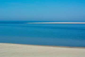 The big blue ocean with a blue sky and a long empty beach in the daylight. Empty European beach