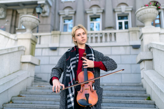 Beautiful girl in coat holding a old violin.