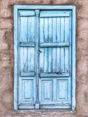 Puerta de madera azul celeste con fondo de piedra gris