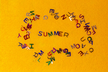 Bright multicolored small letters scattered summer on an yellow background