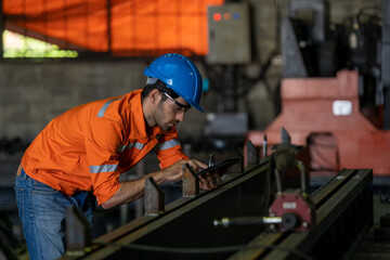 Engineer or factory worker using digital tablet checking inspecting metal component at machine in factory.