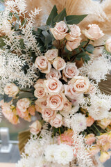 Floristic composition of cream roses, eucalyptus twigs, pampas grass and dahlia.
