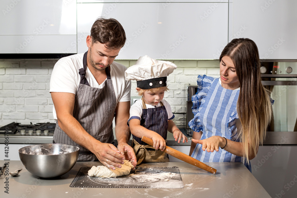 Wall mural happy family in the kitchen. make pizza dough.