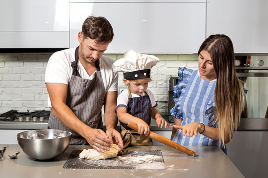 Happy family in the kitchen. Make pizza dough.