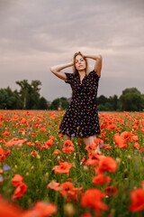 girl in a black dress in a field of poppies