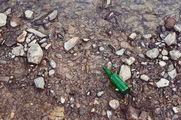 Glass bottle thrownon the river. People left trash on the river bank. Environmental pollution...