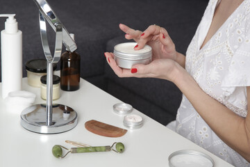 Woman using skin care products in front of the mirror at home. Domestic life, home spa, self care and pampering concept.