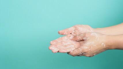 Fototapeta premium Hands washing gesture with foaming hand soap on green and Tiffany Blue background.