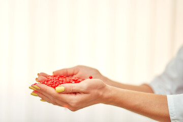 red granules for wax hair removal in a female hand