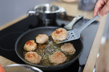 Turn cutlets in frying pan with spatula. How to properly fry cutlets concept