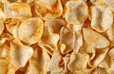 Potato chips with paprika flavor, pepper powder crisps background and texture, top view
