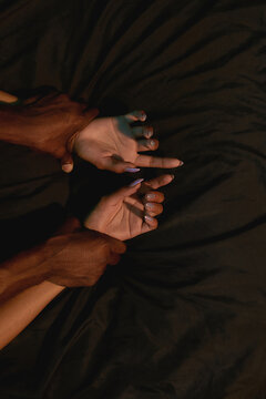 Having sex. Cropped shot of a mixed race couple holding hands while making love on the bed