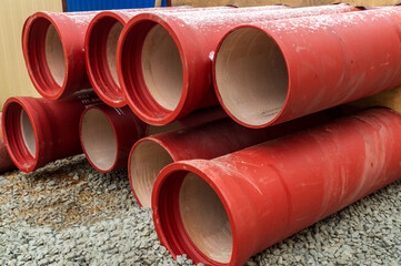 Orange ceramic water pipes are stacked on the street during renovation work