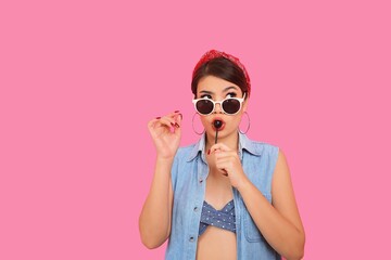 Portrait beautiful woman smiling in bikini holding lollipop in hand over pink background, copy space.