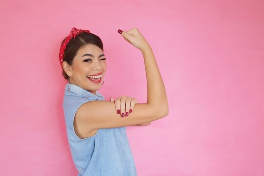 Portrait Strong Woman Showing Her Bicep Over Pink Background,We Can Do It Power Of Woman Concept.