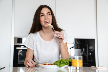 Joyful caucasian woman smiling while having lunch at home kitchen
