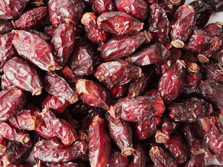 Dried berries of Dog Rose or Rosa canina. Dry fruits of sweet-brier or rose hips on wooden background. Healthy and herbal concept. Selective focus. Natural vitamin, nutritional supplement for health