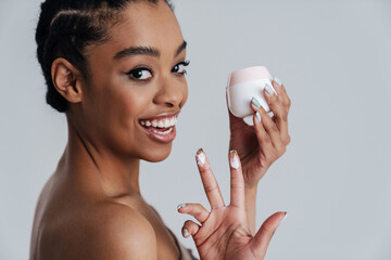 Joyful shirtless african american woman showing face cream