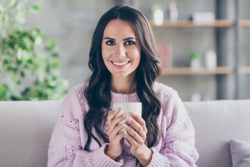 Photo of charming attractive happy lady sit couch hold hands cup of coffee indoors inside house apartment