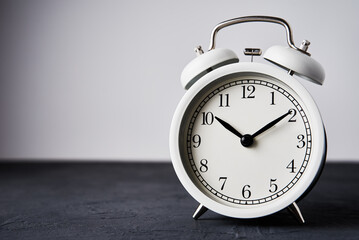 White vintage alarm clock on a black background with copy space