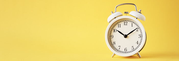 White vintage alarm clock on a yellow background, long banner with copy space